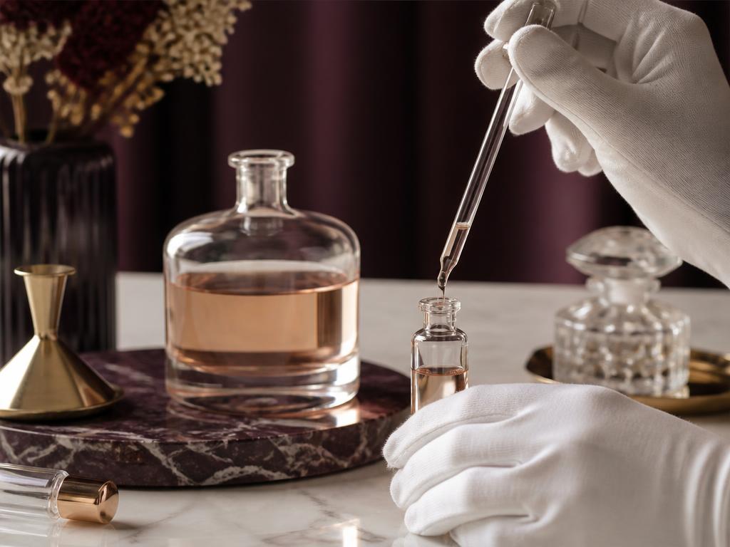 Gehandschoende handen vullen een kleine decantflacon met een pipet op een marmeren bank